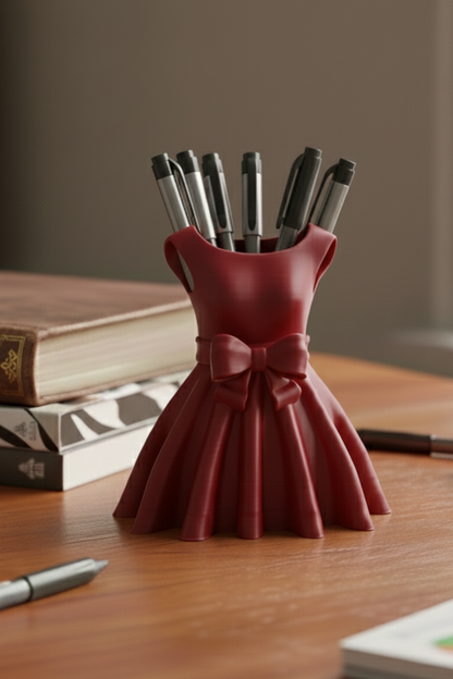 Red dress-shaped pen holder with pens on a wooden surface
